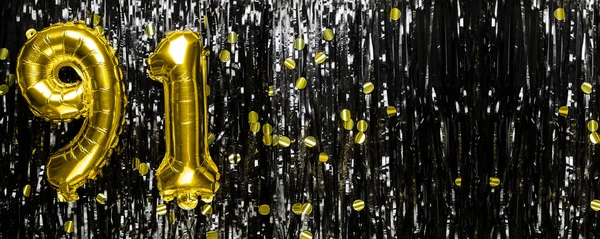 Gold foil balloon number number 91 on a background of black tinsel decoration. Birthday greeting card, inscription ninety-one. Anniversary event. Banner. copy space.