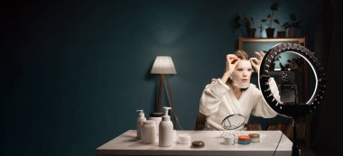 Bornozlu genç bir güzellik blogcusu. Cilt tavsiyesi ile video kaydediyor. İç hatlarda akıllı telefondan canlı yayın yapıyor. Pankart. Boşluğu kopyala