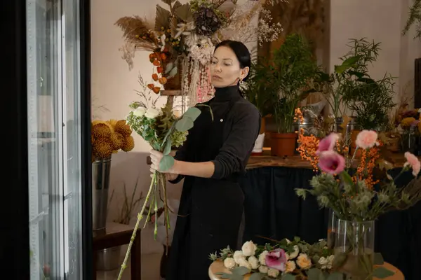 Small business and Flower delivery concept. Female florist in a flower shop. Floral design studio, making decorations and arrangements. Copy space