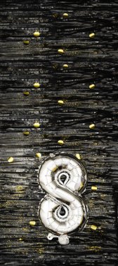 Altın konfetiyle siyah süslemenin arka planında 8 numaralı gümüş folyo balonu. Doğum günü tebrik kartı, sekizinci yazı. Yıldönümü etkinliği. Dikey Sancak. Boşluğu kopyala.