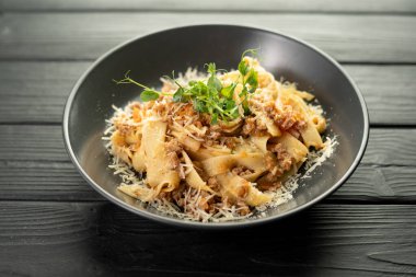 Kıyma, sebze, maydanoz ve parmesan peynirli Farfalle makarnası siyah bir arka planda servis ediliyor. Boşluğu kopyala