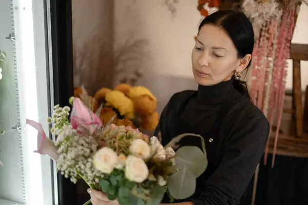 Small business and Flowers delivery. Female florist creating bouquet in flower shop. Floral design studio, making decorations and arrangements. Copy space