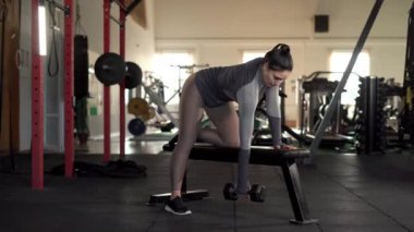 Güç, spor ve zindelik konsepti. Spor salonunda halterin üstünde duran bir kadın egzersiz yapıyor. Boşluğu kopyala