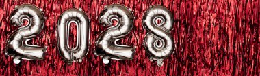 Kırmızı zemin üzerinde 2028 rakam balonları. Yeni yıl kompozisyonu. Pankart