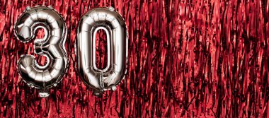 30 numaralı gümüş folyo balonu. Doğum günü tebrik kartında 30 yazılıydı. Yıldönümü kutlaması. Pankart. Kırmızı arka planda gümüş rakam. Boşluğu kopyala