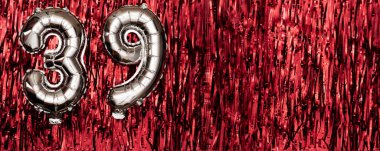 Gümüş folyo balonu 39 numara. 39. yazıyla birlikte doğum günü tebrik kartı. Yıldönümü kutlaması. Pankart. Kırmızı arka planda gümüş rakam. Boşluğu kopyala