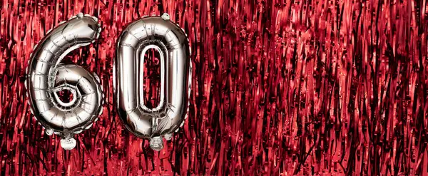 Silver foil balloon number sixty. Birthday or anniversary card with the inscription 60. Red tinsel background. Anniversary celebration. Banner. copy space