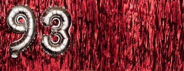 93 numaralı gümüş folyo balonu. Doğum günü ya da yıldönümü kartında 93 yazılıydı. Kırmızı süs arkaplanı. Yıldönümü kutlaması. Pankart. Boşluğu kopyala