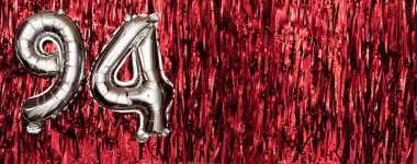 94 numaralı gümüş folyo balonu. Doğum günü ya da yıldönümü kartında 94 yazılıydı. Kırmızı süslemeler. Yıldönümü kutlaması. Pankart. Boşluğu kopyala