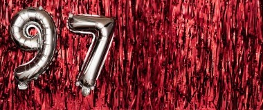 Doksan yedi numaralı gümüş folyo balonu. Doğum günü ya da yıldönümü kartında 97 yazılıydı. Kırmızı süs arkaplanı. Yıldönümü kutlaması. Pankart. Boşluğu kopyala