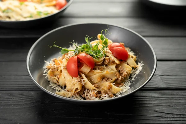 Tagliatelle al ragu. Italian pasta with meat bolognese sauce, tomatoes and parmesan cheese on dark wooden background. Copy space