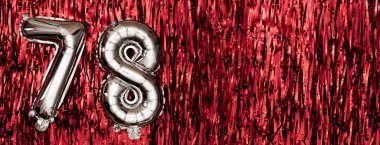 78 numaralı gümüş folyo balonu. 78 yazılı doğum günü ya da yıldönümü kartı. Kırmızı süslemeli arka plan. Yıldönümü kutlaması. Pankart. Boşluğu kopyala