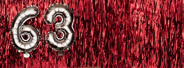 Silver foil balloon number, digit sixty-three on red background. Birthday greeting card with inscription 63. Anniversary celebration event. Banner. Numerical digit. Copy space