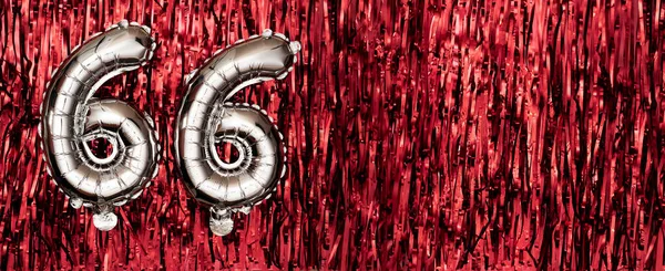 Silver foil balloon number, digit sixty-six on red background. Birthday greeting card with inscription 66. Anniversary celebration event. Banner. Numerical digit. Copy space