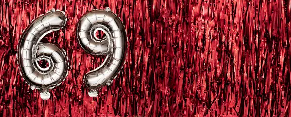 Silver foil balloon number, digit sixty-nine on red background. Birthday greeting card with inscription 69. Anniversary celebration event. Banner. Numerical digit. Copy space