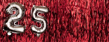 25 numaralı gümüş folyo balonu. Üzerinde 25 yazan doğum günü tebrik kartı. Yıldönümü kutlaması. Pankart. Kırmızı arka planda gümüş rakam. Boşluğu kopyala