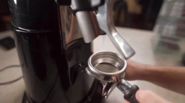 Kahveci kahve çekirdeğini öğütücü makinesiyle öğütür. Espresso makinesi için portafilter içine taze kahve çekirdekleri. Yakın plan.