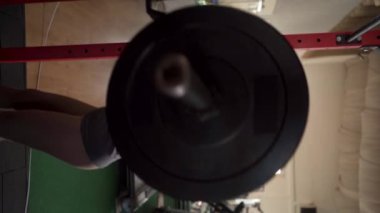Spor giyimli, kaslı genç bir kadın spor salonunda ağırlık kaldırıyor. Dikey video
