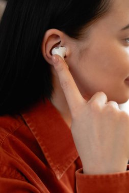 Kulağında kulaklık tutan Latin kökenli genç bir kadın. Boşluğu kopyala
