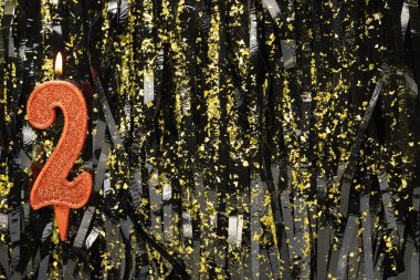 Doğum günü ya da yıldönümü kutlaması için koyu renkli arka planda 2 numaralı mumu yakmak. Pankart. Boşluğu kopyala