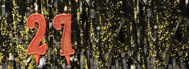 Işıltılı arka planda kırmızı doğum günü mumları yakmak, 27 numara. Pankart. Boşluğu kopyala