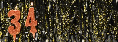 Parlak süslemeli arka planda kırmızı doğum günü mumları yakmak, 34 numara. Pankart. Boşluğu kopyala