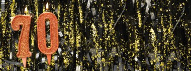 Işıltılı arka planda kırmızı doğum günü mumları yakmak, 70 numara. Pankart. Boşluğu kopyala