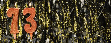 Işıltılı arka planda kırmızı doğum günü mumları yakmak, 73 numara. Pankart. Boşluğu kopyala