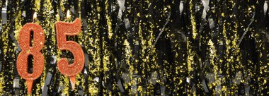 Işıltılı arka planda kırmızı doğum günü mumları yakmak, 85 numara. Pankart. Boşluğu kopyala