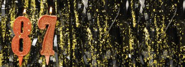 Işıltılı arka planda kırmızı doğum günü mumları yakmak, 87 numara. Pankart. Boşluğu kopyala