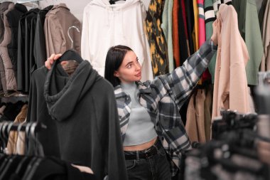 Giyim mağazasından kıyafet seçen genç ve güzel bir bayan alıcı. Satış sırasında moda mağazasından kıyafet alıyor. Boşluğu kopyala