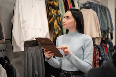 Moda mağazasında çalışırken tablet kullanan güzel bir genç kadın. Boşluğu kopyala