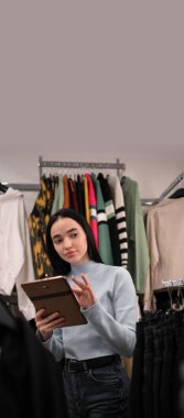 Giyim mağazasında. Kadın yönetici şık moda koleksiyonu yapmak için dijital tablet kullanır. Küçük işletme sahibi kavramı