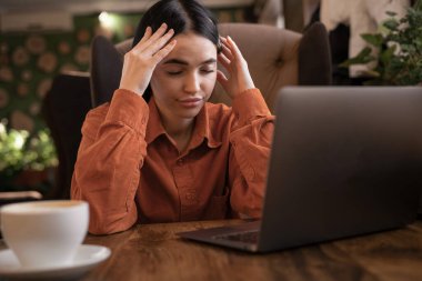 Kafede çalışan, bilgisayarında stres ve baş ağrısı olan çekici genç bir kadın. Ağrısı olan, kaygılı ya da dizüstü bilgisayarda yorgun bir kız. Boşluğu kopyala