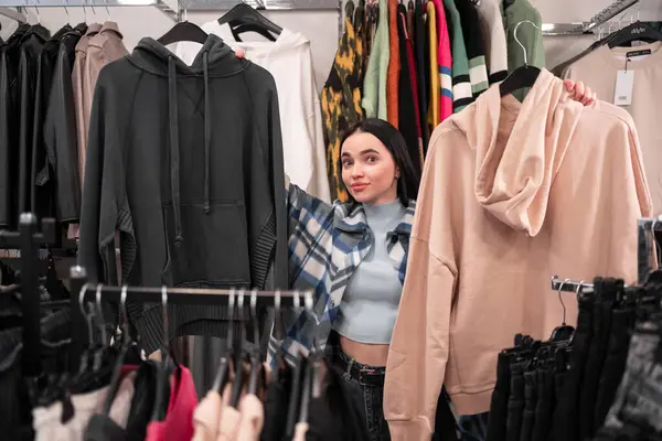 Casual young woman chooses spring clothes in a clothing store. Copy space