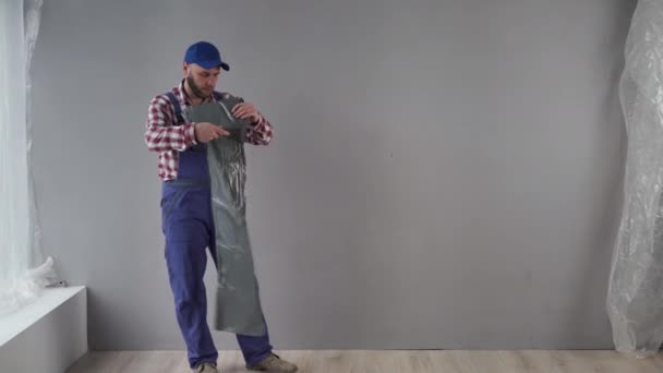 Young Caucasian Man Explaining How Fixing Film Floor Painting Wall — Stock Video