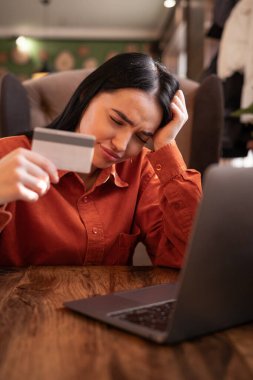 Çevrimiçi dolandırıcılık ve aldatma konsepti. Kafe 'de elinde kredi kartıyla dolandırılan ve hayal kırıklığına uğramış bir kadın ve online mağazadan ya da e-bankacılık ödemesinden alışveriş yapmaya çalışıyor. Boşluğu kopyala
