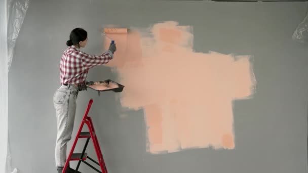 그녀의 새로운 가정의 방에서 사다리에 페인트 롤러와 아파트에서 리노베이션을 만드는 — 비디오