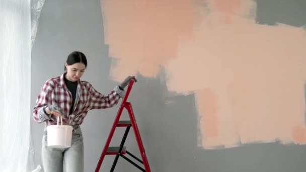 リノベーションアパート 若い幸せな女性は自分の手で家を修理する 新しい家に壁を描く コピースペース — ストック動画