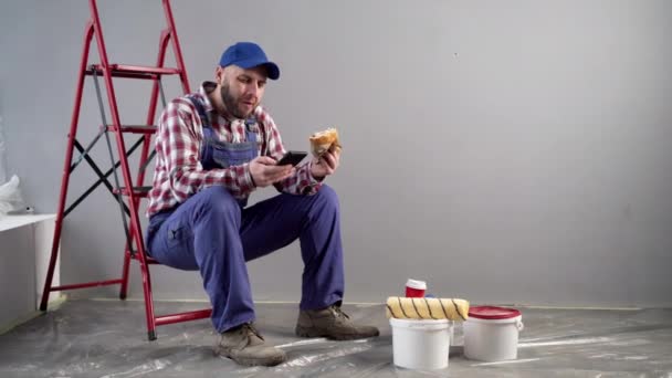 Professional Painter Having Lunch Burger Uses Mobile Phone Chatting Friends — Stock Video