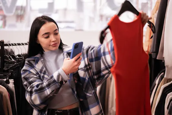 Clothes store customer or owner taking a picture of a clothing item in store in order to advertise on social media. fashion store online. sale, fashion, consumerism and people concept