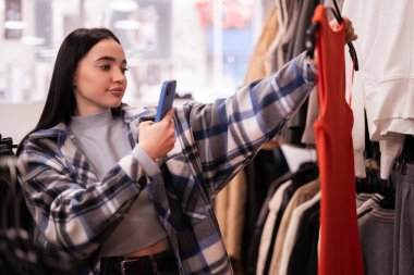 Küçük işletme sahibi, sosyal medyada reklamını yapmak için mağazasında elbise fotoğrafı çekiyor. Moda mağazası online. Boşluğu kopyala