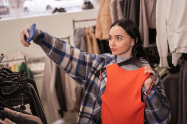 Alışveriş yapan genç bir kadın alışveriş merkezinde sosyal iletişim için fotoğraf çekiyor. Boşluğu kopyala