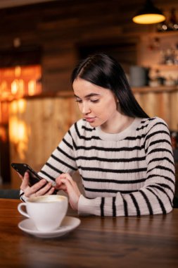 Kahveli neşeli blogcu akıllı telefondan gelen mesajları okuyor. Cep telefonundan yayın yapan genç pozitif öğrenci. Boşluğu kopyala