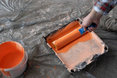 Kapalı alanda boya silindiri kullanan bir inşaatçının yakın çekimi, tepsiden boya alımı. Yeni ev yenileme konsepti