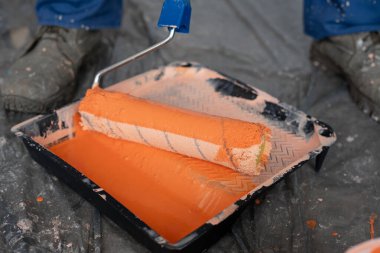 Ressam ve dekorasyon için aletler. Tepside turuncu boya ve paten fırçası var. Yakın plan.