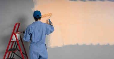 Kadın ressam bir duvar boyuyor, arkadan bakıyor. Profesyonel müteahhit yeni evde tamirat yapıyor. Pankart. Boşluğu kopyala