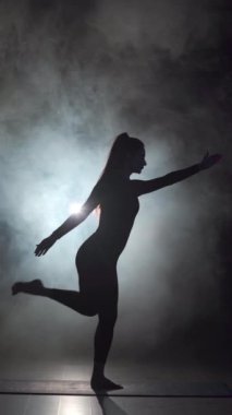 Siyah spor salonunda yoga yapan siluetli bir kadın ya da buharlı bir stüdyo. Boşluğu kopyala