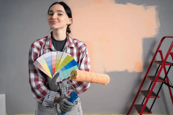 portrait of painter woman with paint roller and ladder showing a color palette. Copy space