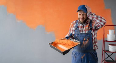 Turuncu duvar arkasında sakallı bir ressam. Kafası karışık bir yüz ifadesi var. Boşluğu kopyala